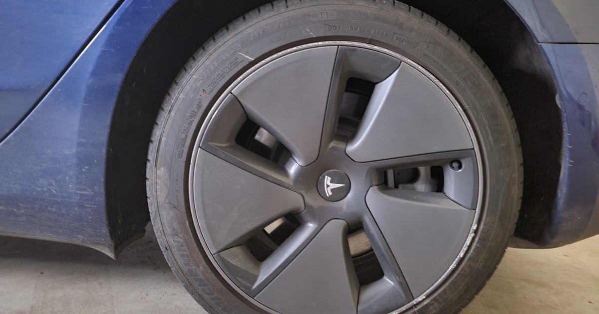 Close-up of a Tesla aero wheel cover on a blue Model 3