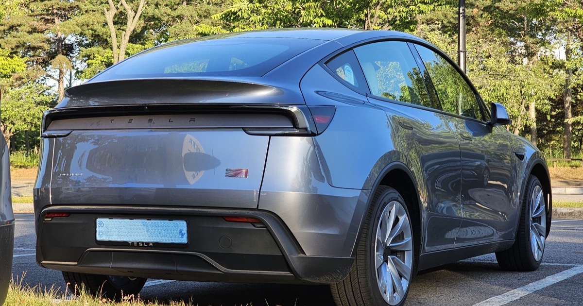Silver Tesla Model Y Juniper, rear three-quarter view with tinted rear glass